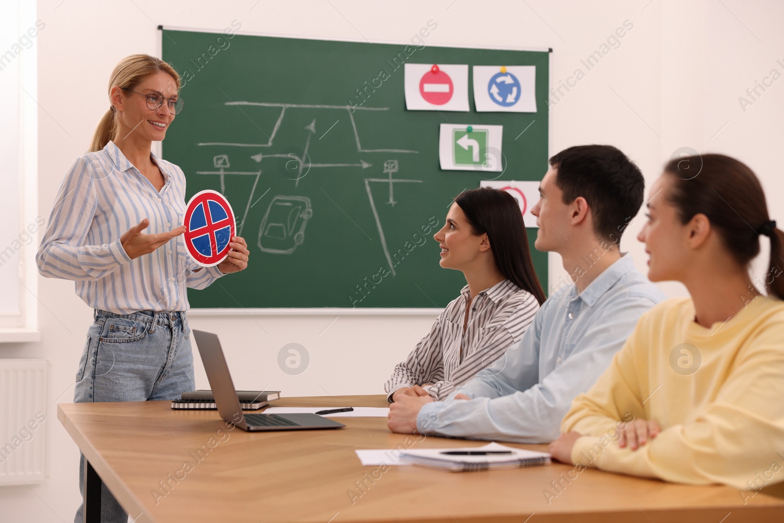 Photo of Teacher showing No Stopping road sign to audience in driving school