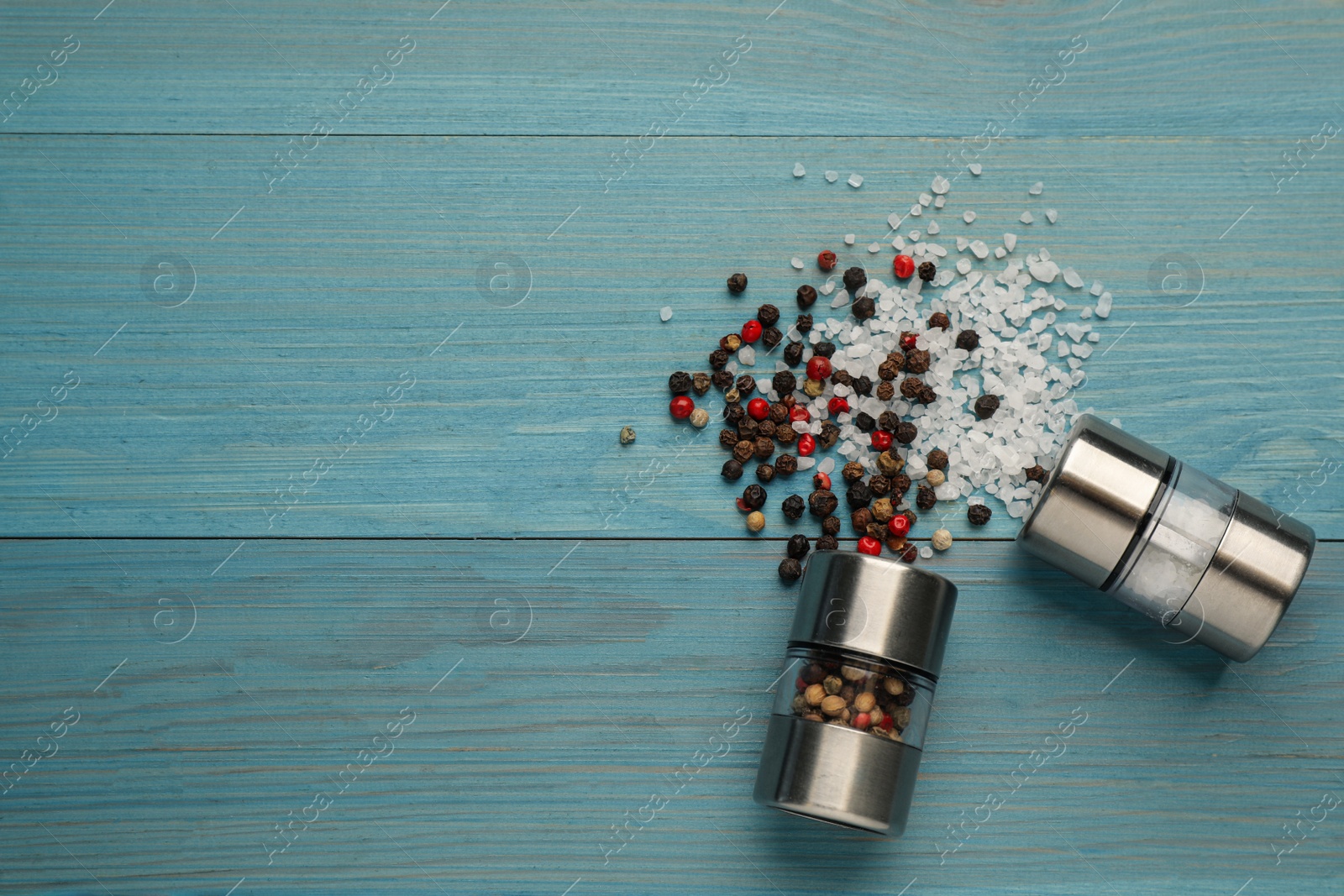 Photo of Salt and pepper shakers on turquoise wooden table, flat lay. Space for text