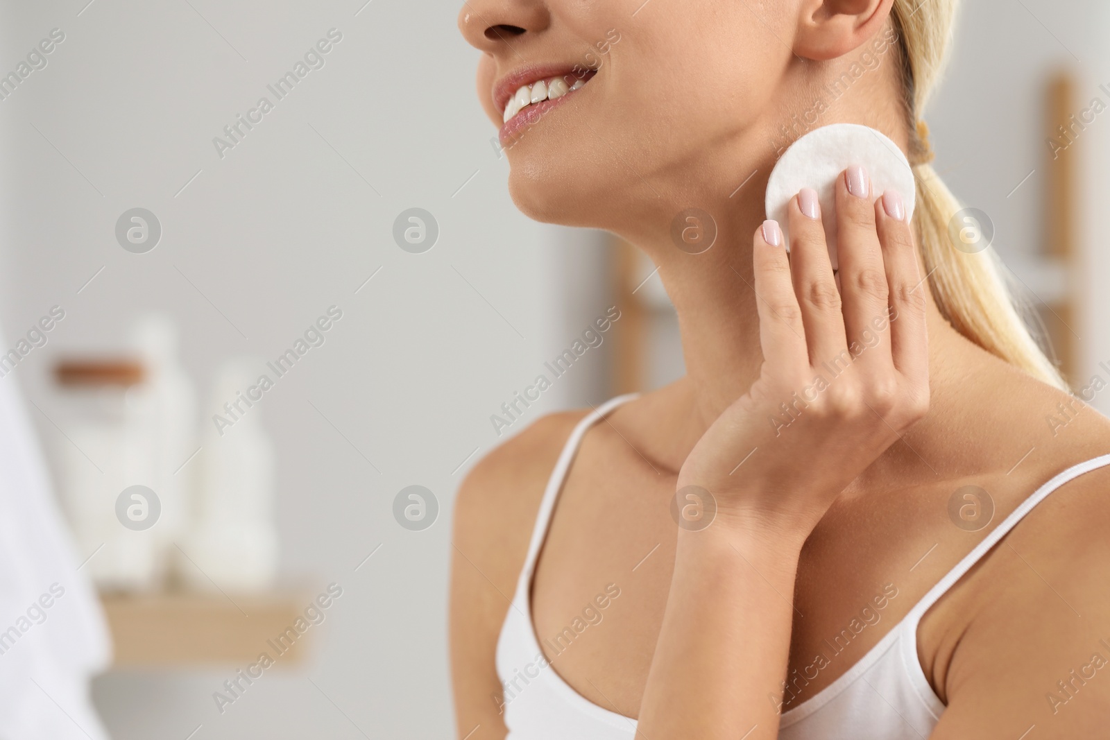 Photo of Smiling woman removing makeup with cotton pad indoors, closeup. Space for text