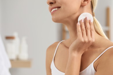 Smiling woman removing makeup with cotton pad indoors, closeup. Space for text