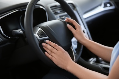 Photo of Young woman sitting in driver's seat of new car at salon