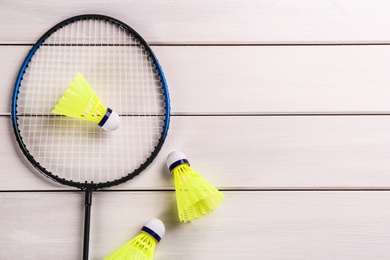 Photo of Badminton racket and shuttlecocks on white wooden table, flat lay. Space for text