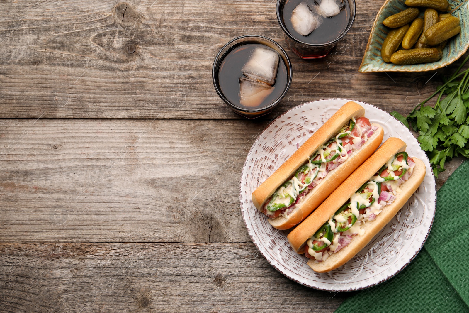 Photo of Delicious hot dogs with onion, chili pepper and sauce served on wooden table, flat lay. Space for text