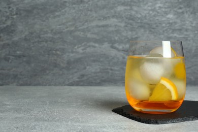 Photo of Delicious cocktail with orange, yellow cherry and ice balls on grey table, space for text