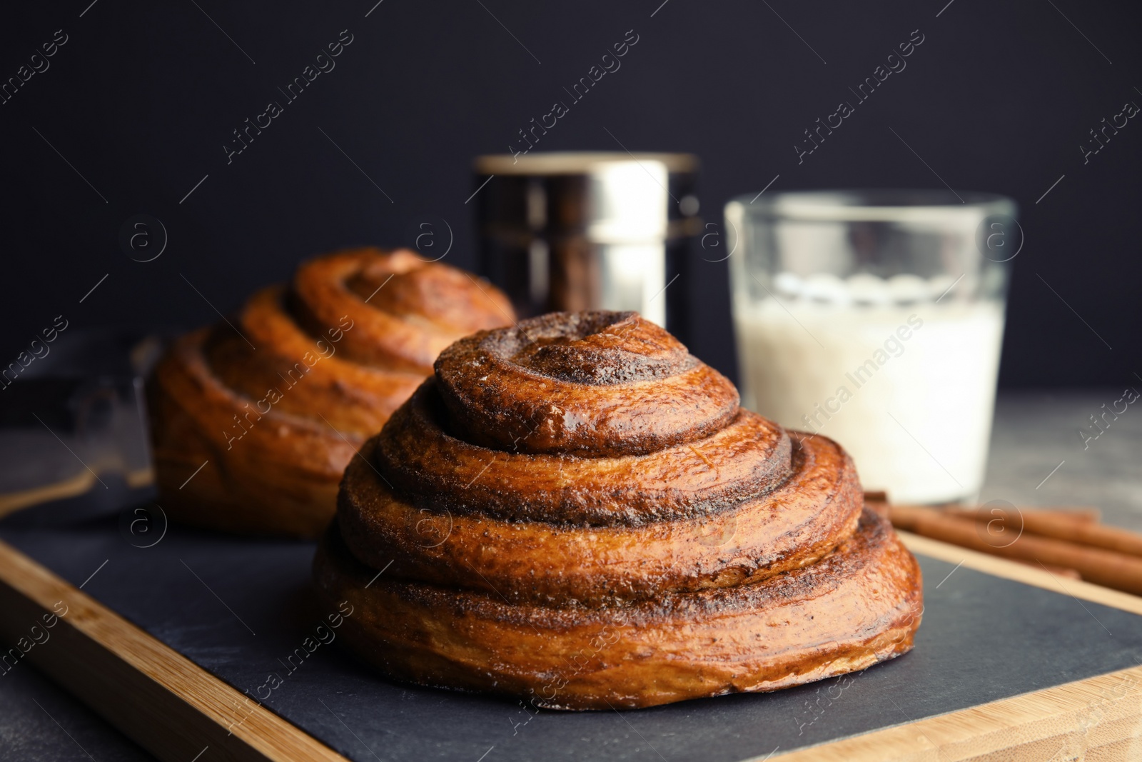 Photo of Board with baked cinnamon rolls on table, closeup