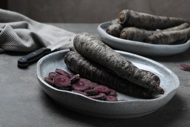 Photo of Fresh raw black carrots on grey plate