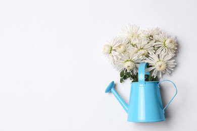 Photo of Watering can with beautiful flowers on white background, top view. Space for text