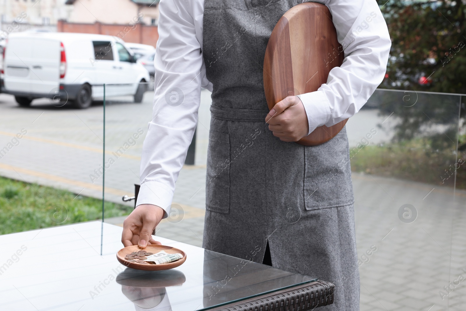 Photo of Waiter taking tips from wooden table in outdoor cafe, closeup