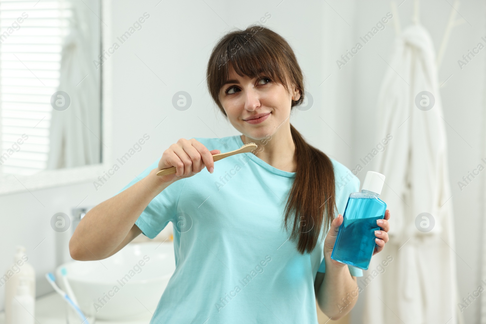 Photo of Young woman with mouthwash and toothbrush in bathroom