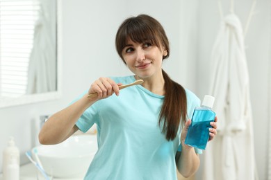 Young woman with mouthwash and toothbrush in bathroom