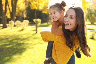 Photo of Happy woman with little daughter in sunny park. Autumn walk