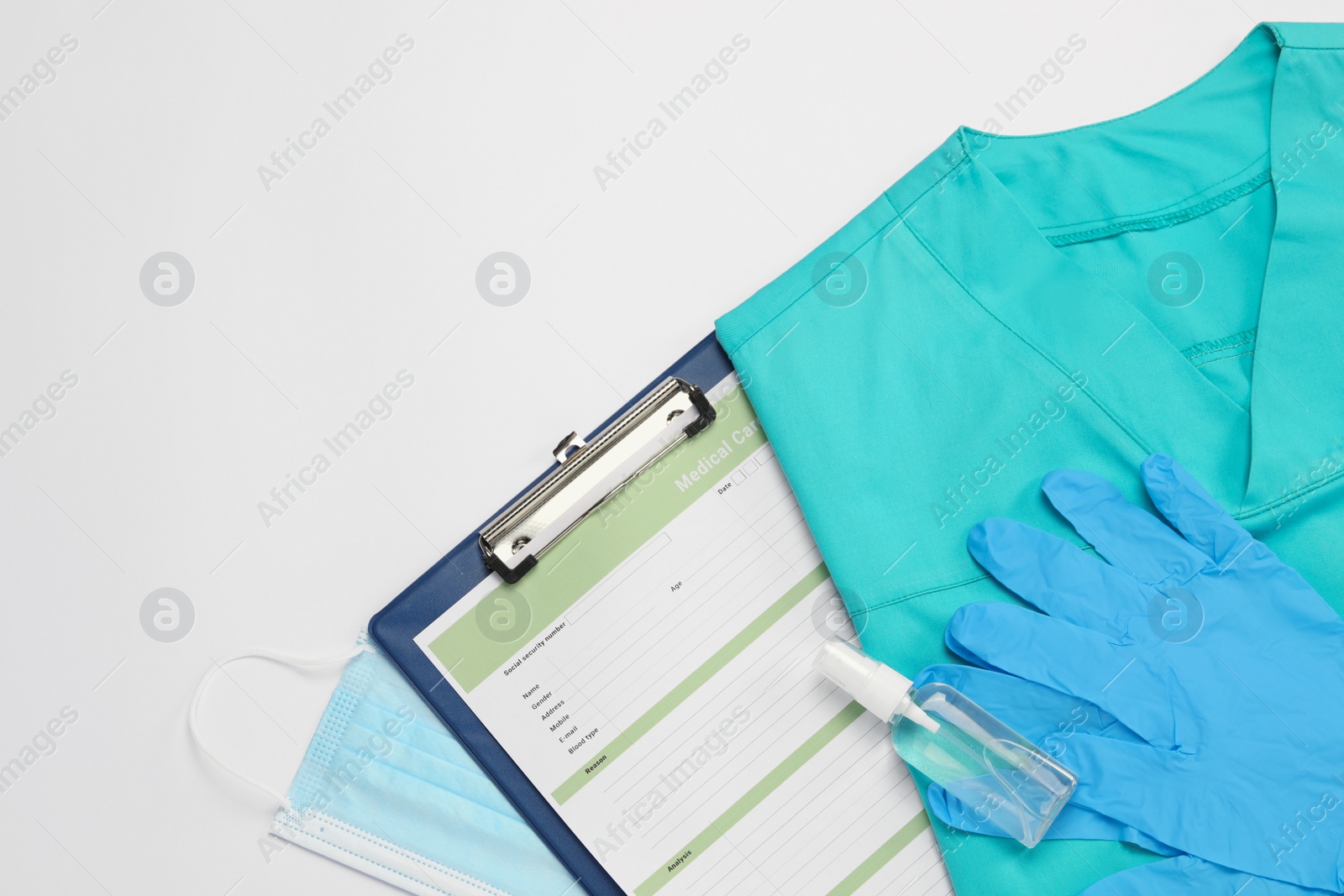 Photo of Flat lay composition with medical uniform and clipboard on white background. Space for text