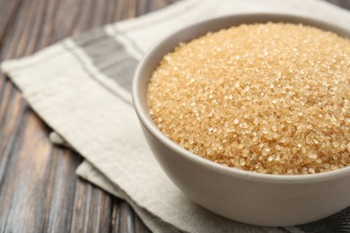 Brown sugar in bowl on wooden table, closeup