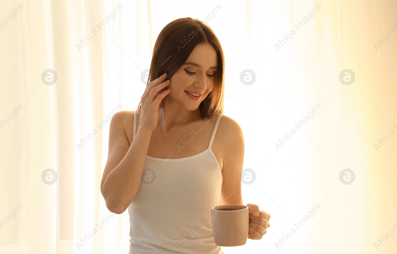 Photo of Young woman with cup near window at home. Lazy morning