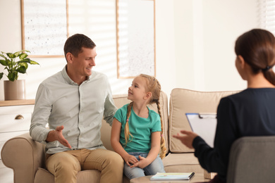 Little girl and her father on appointment with child psychotherapist indoors