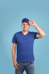 Photo of Happy man in cap and tshirt on light blue background. Mockup for design