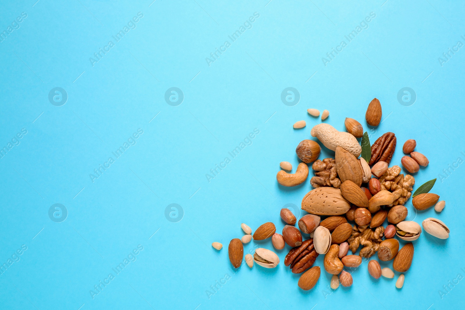 Photo of Different delicious nuts on light blue background, flat lay. Space for text