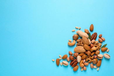 Photo of Different delicious nuts on light blue background, flat lay. Space for text