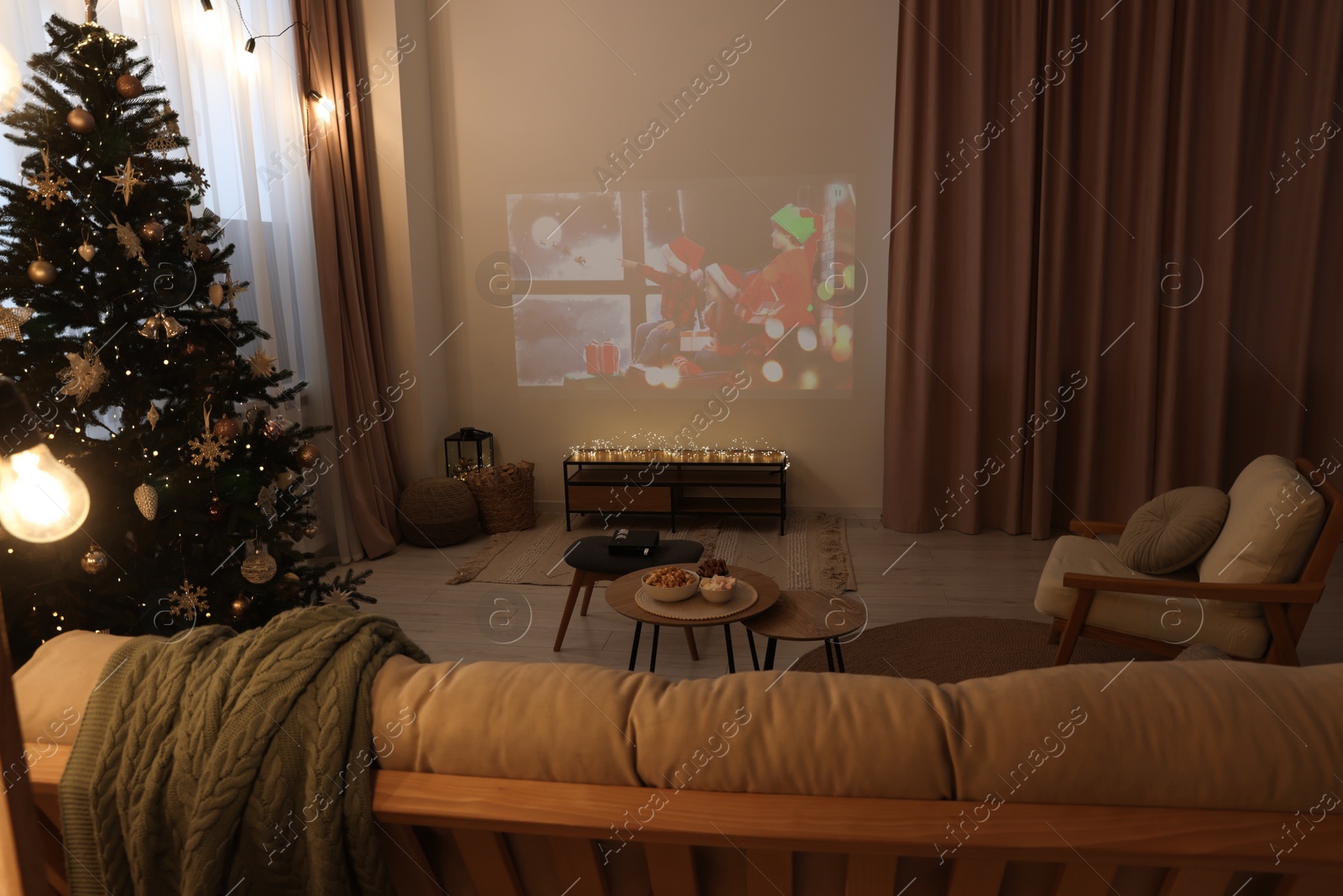 Photo of Video projector with Christmas movie in cosy room. Winter holidays atmosphere