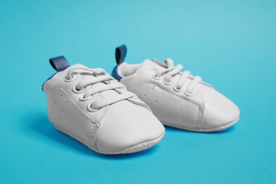 Photo of Pair of cute baby shoes on light blue background