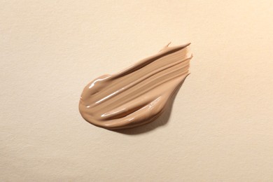 Photo of Swatch of skin foundation on beige background, top view