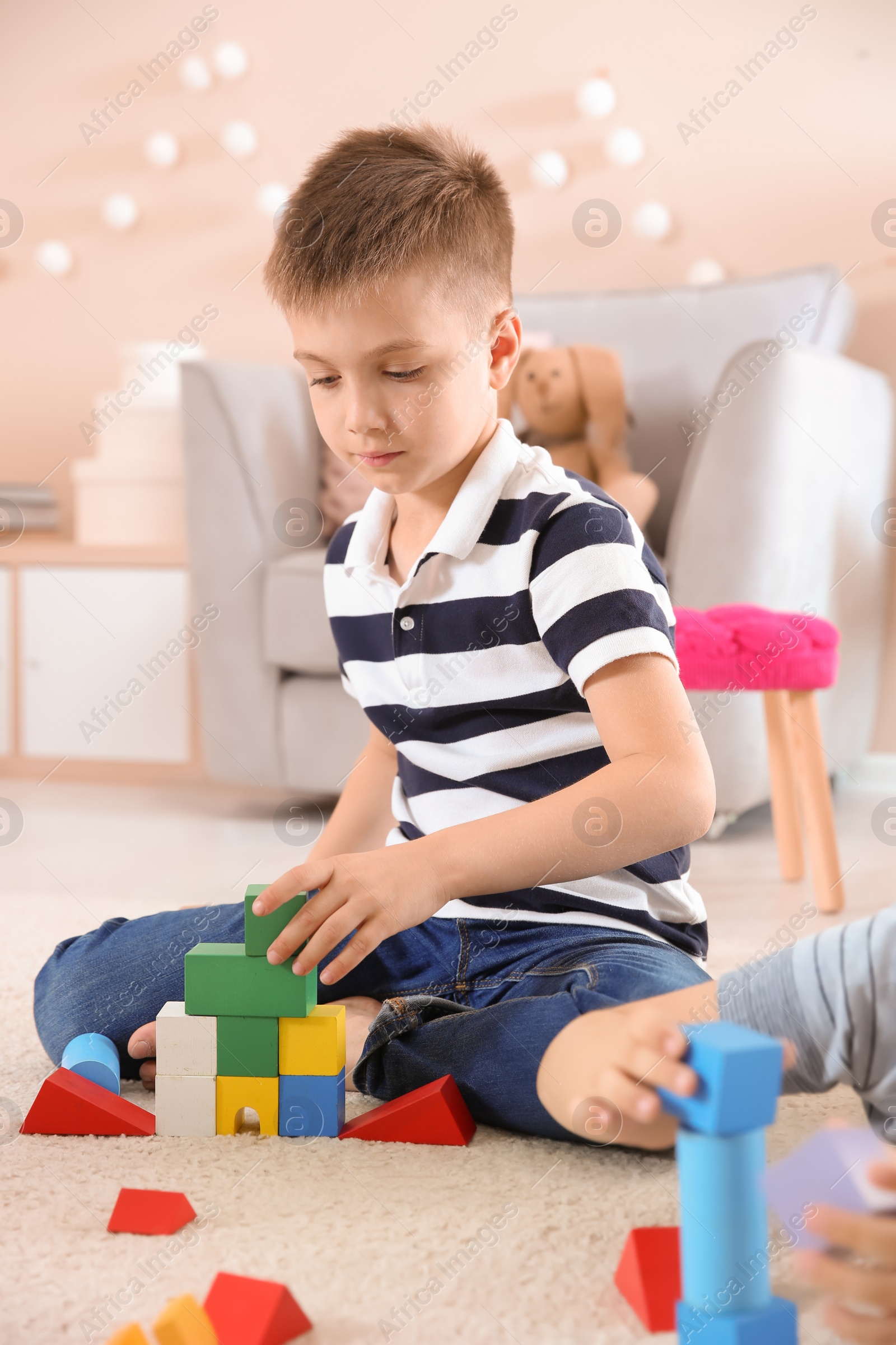 Photo of Cute little child playing with building blocks on floor, indoors