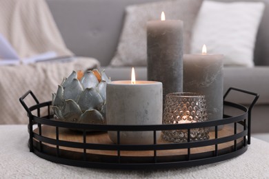 Photo of Tray with burning candles on ottoman indoors