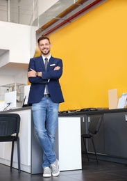 Salesman standing in modern auto dealership. Buying new car