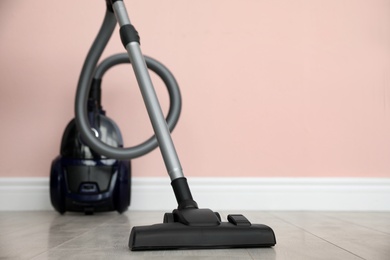 Photo of Modern vacuum cleaner near pink wall indoors, space for text