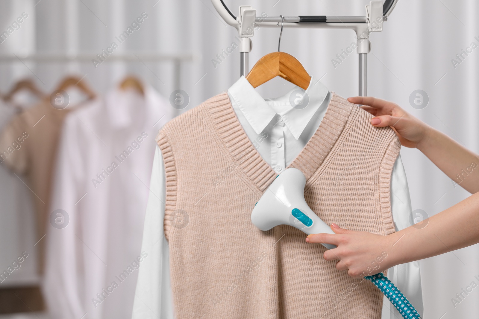 Photo of Woman steaming clothes on hanger at home, closeup
