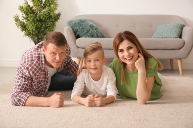 Photo of Happy family lying on cozy carpet at home