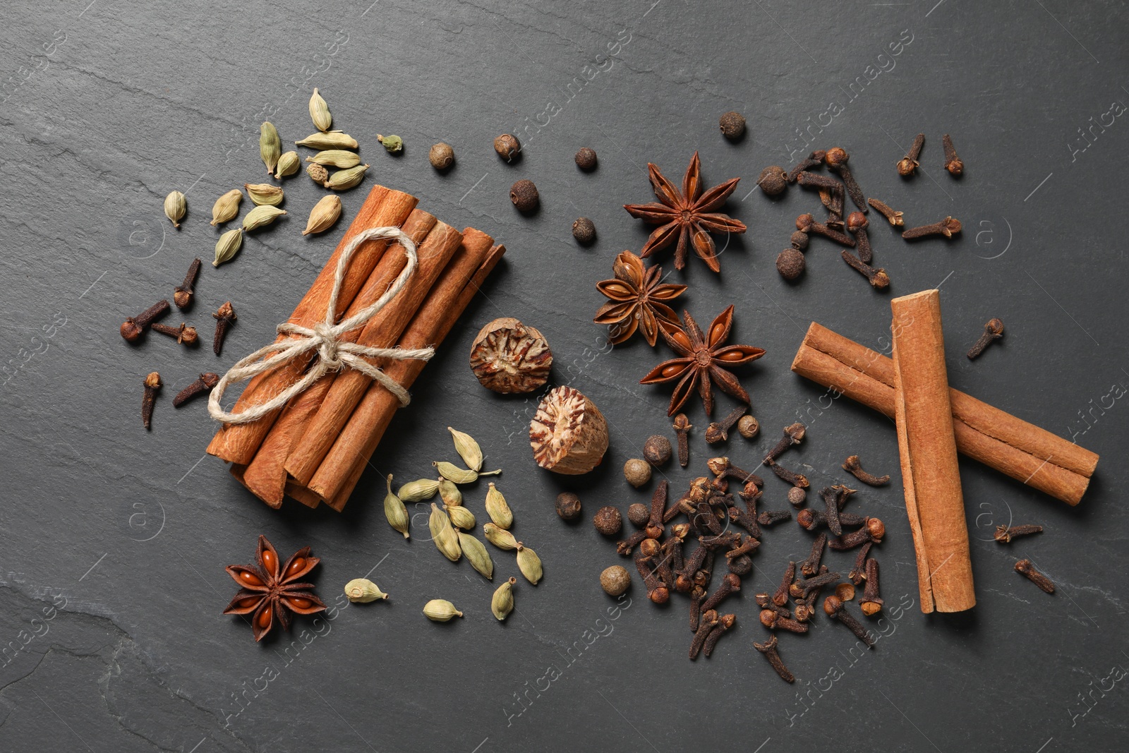 Photo of Different spices on dark gray textured table, flat lay
