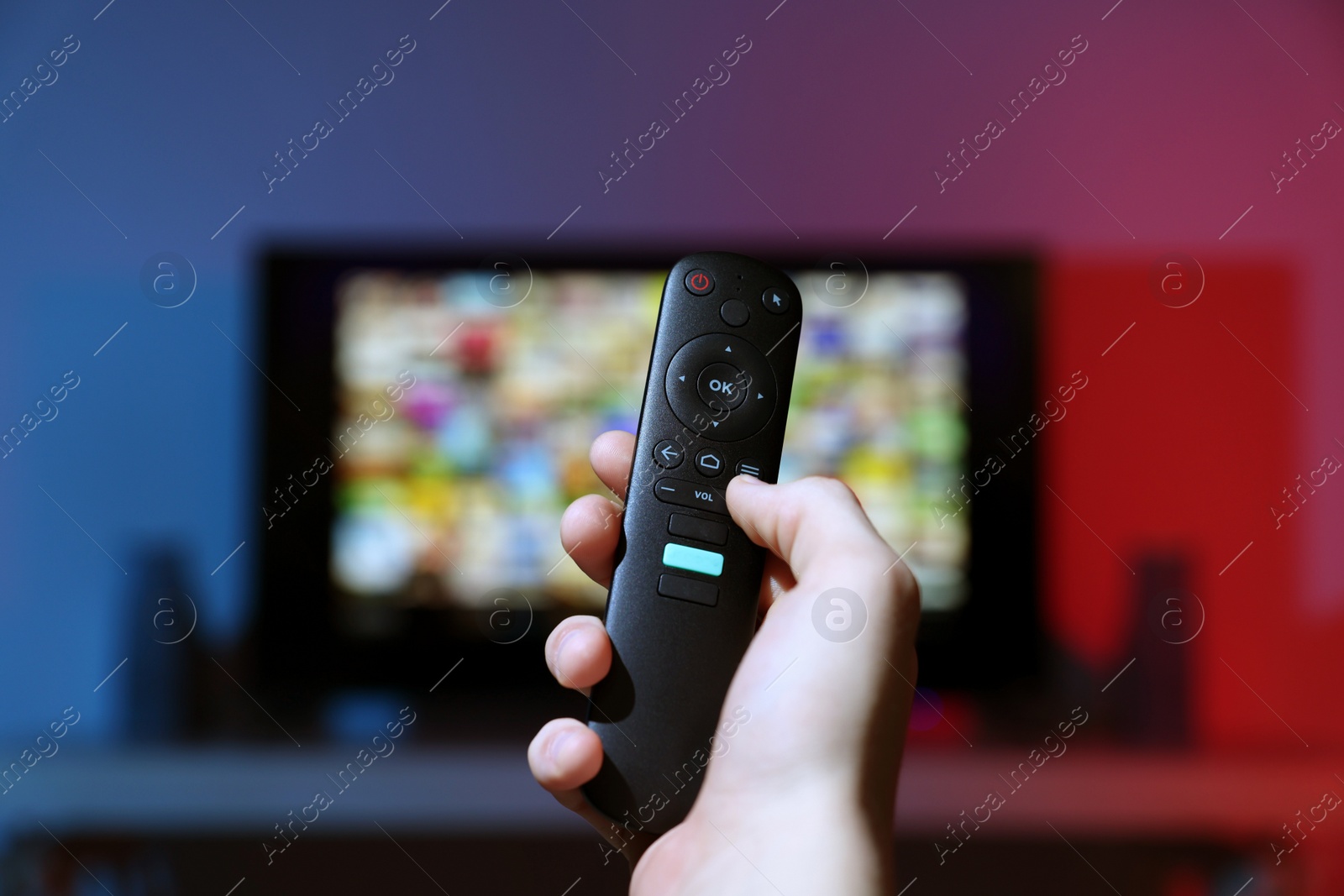 Photo of Woman switching channels on TV set with remote control at home, closeup