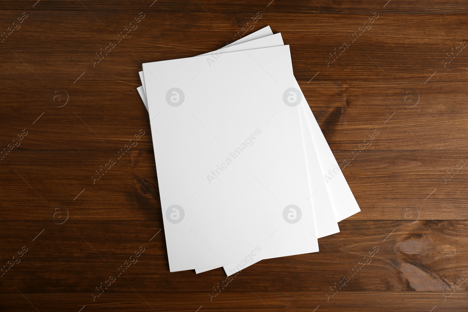 Photo of Stack of blank paper sheets on wooden table, top view. Brochure design