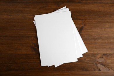 Photo of Stack of blank paper sheets on wooden table, top view. Brochure design