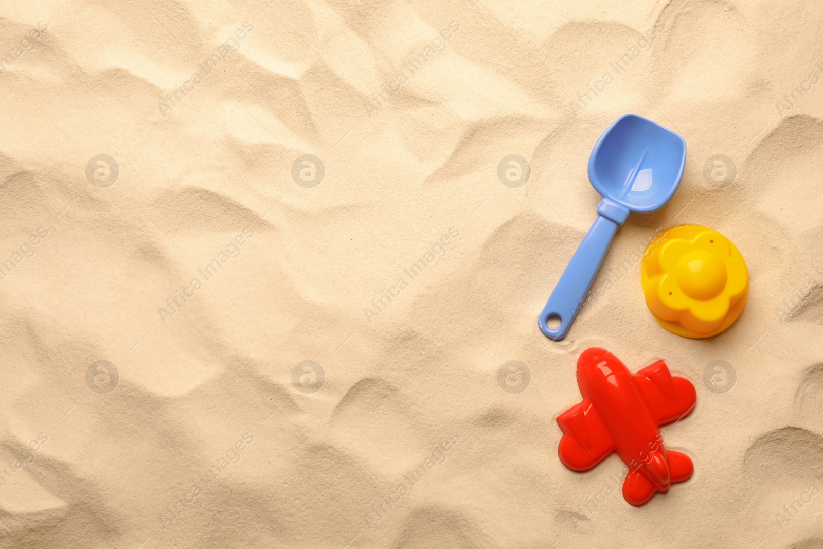 Photo of Flat lay of beach toy kit on sand, space for text. Outdoor play