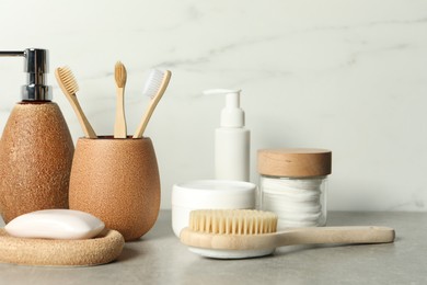 Different bath accessories and personal care products on gray table near white marble wall