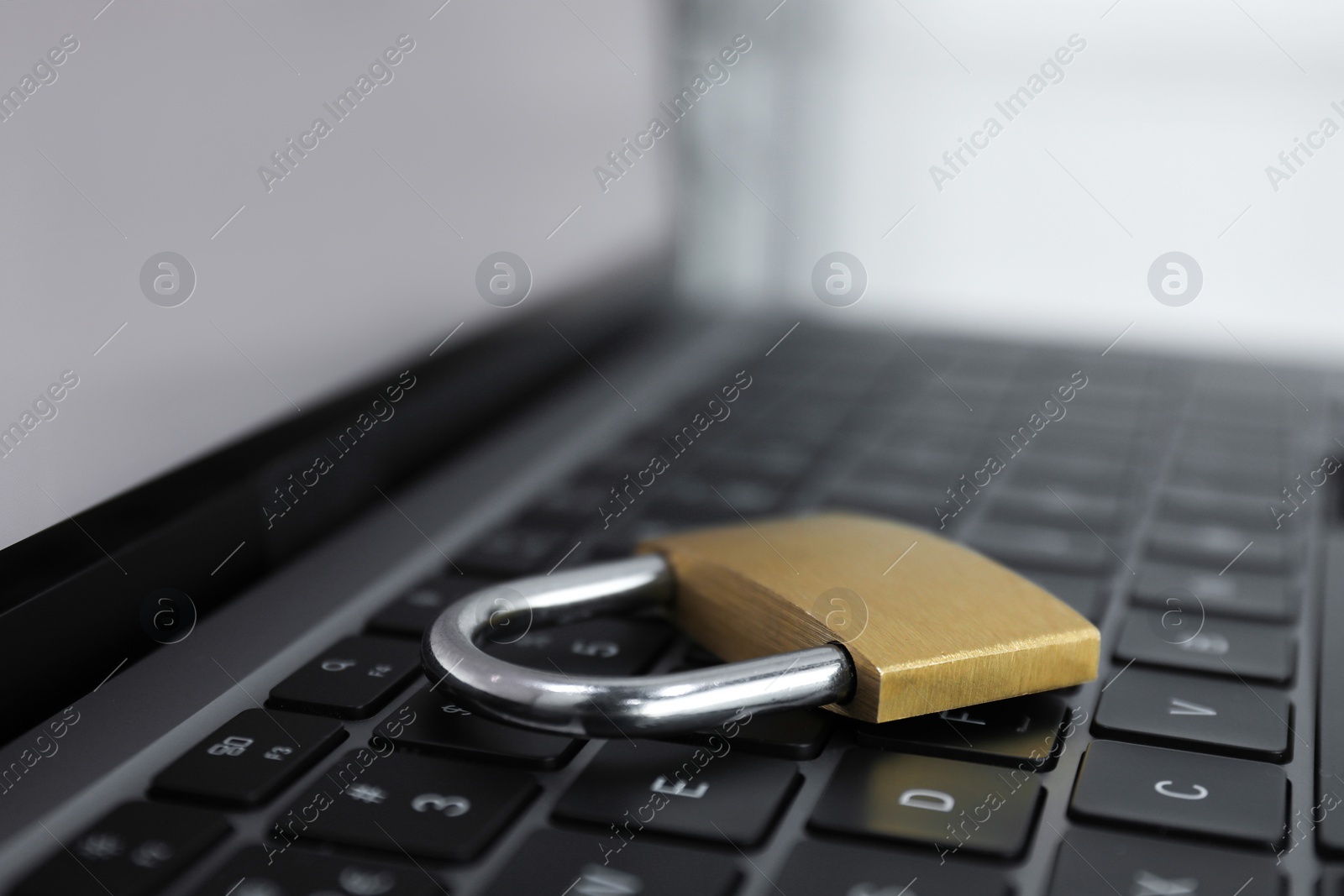 Photo of Cyber security. Metal padlock on laptop, closeup