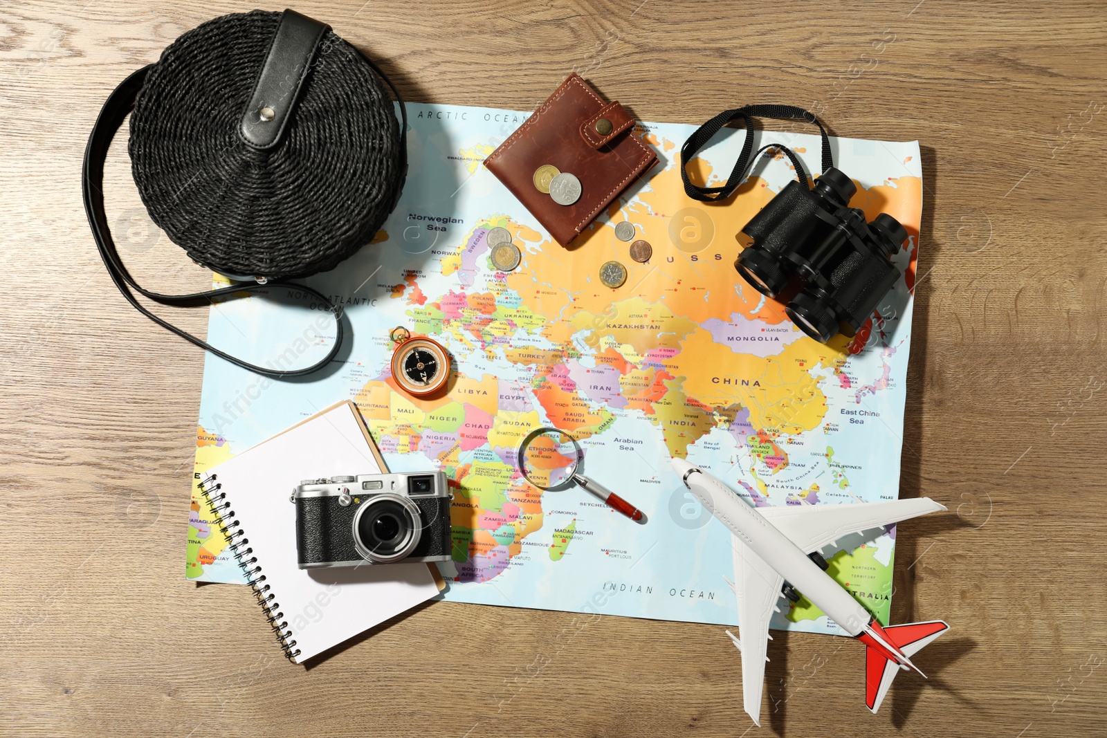 Photo of World map and items on wooden background, flat lay. Travel during summer vacation