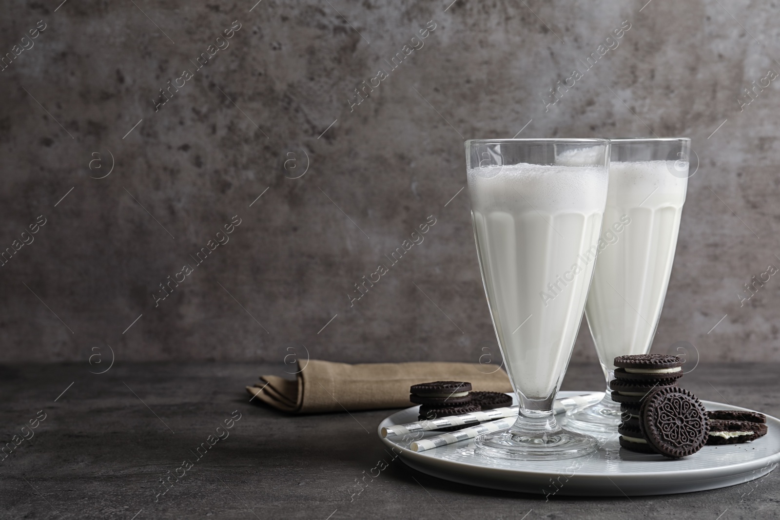 Photo of Glasses of milk with chocolate cookies on table against grey background, space for text