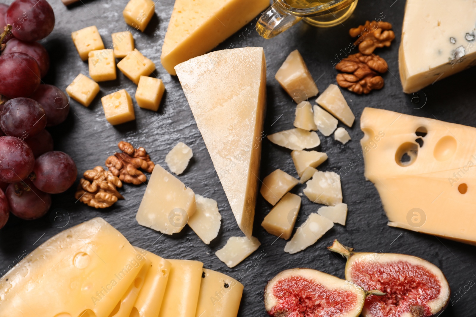 Photo of Composition with different types of delicious cheese and snacks on slate board, above view