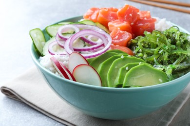Photo of Delicious poke bowl with salmon, seaweed and vegetables served on light grey table, closeup