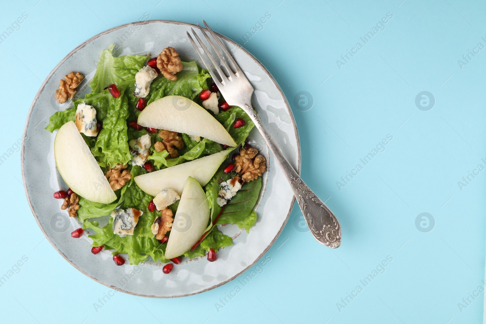 Photo of Delicious pear salad on light blue background, top view. Space for text