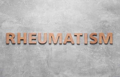 Photo of Word Rheumatism made of wooden letters on light gray textured background, top view
