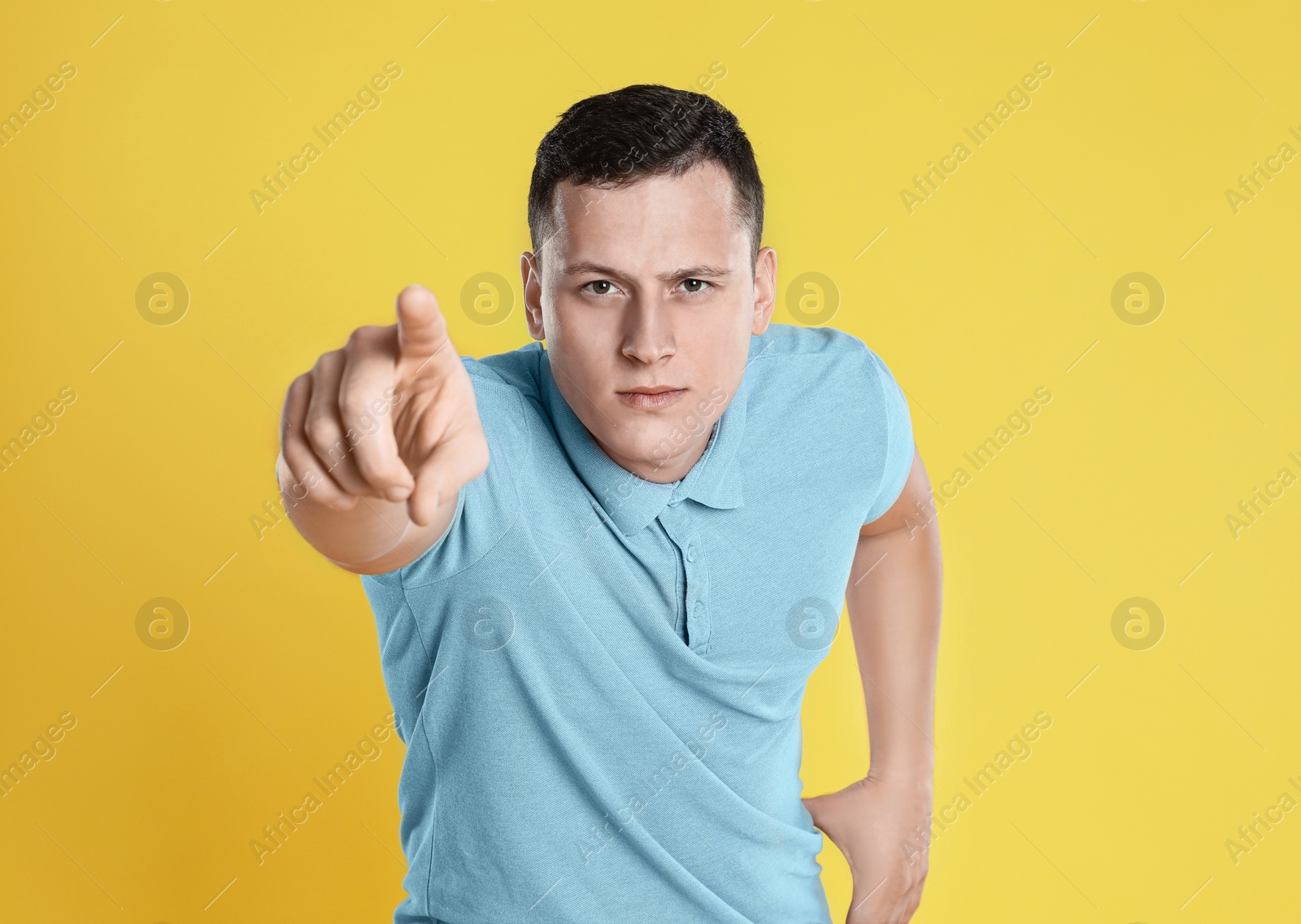 Photo of Grumpy young man posing on yellow background