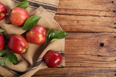 Photo of Ripe red apples with leaves on wooden table, flat lay. Space for text