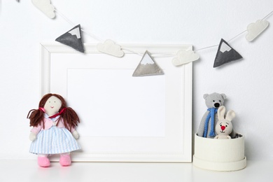 Photo of Soft toys and photo frame on table against white background, space for text. Child room interior
