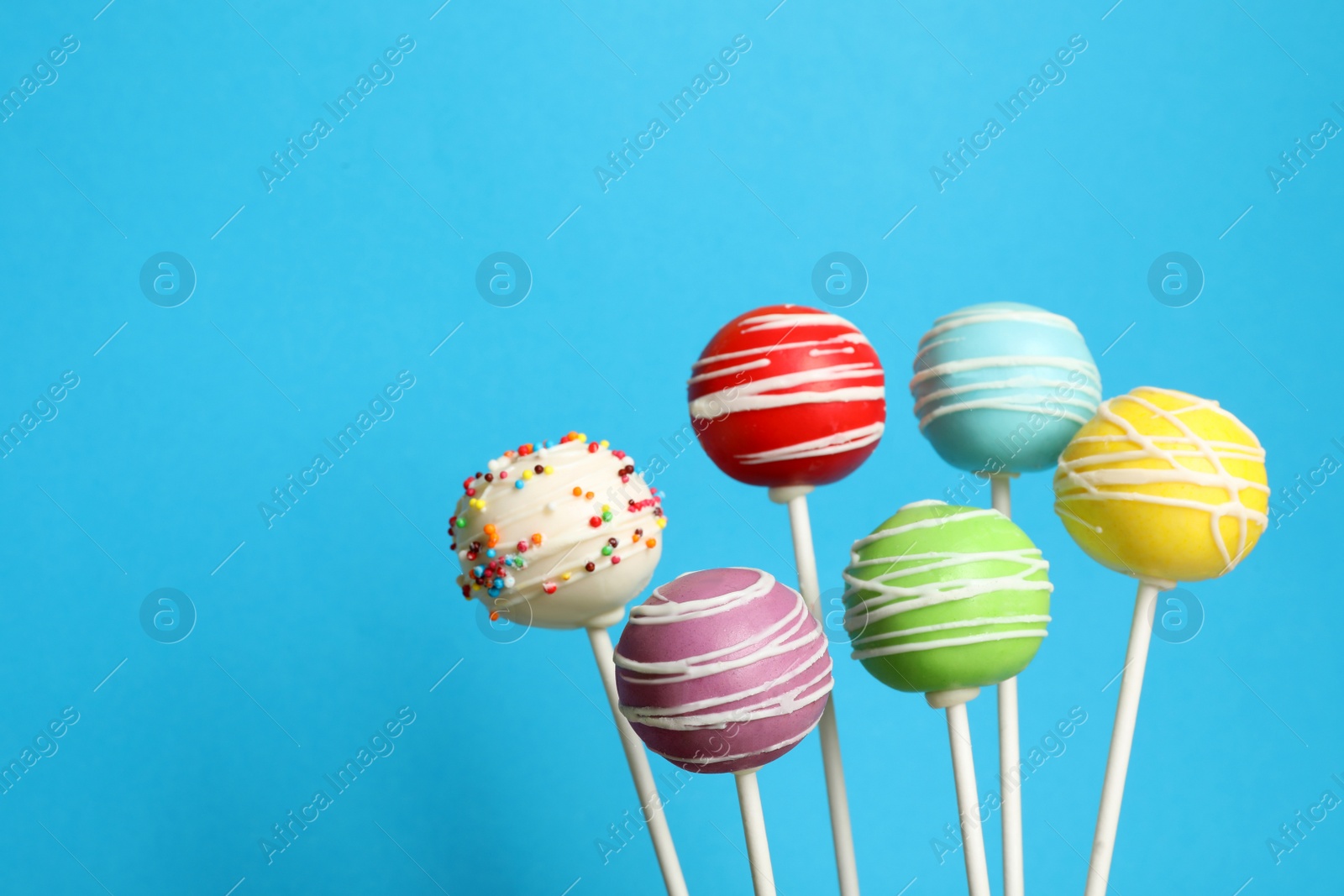 Photo of Many bright delicious cake pops on color background. Space for text