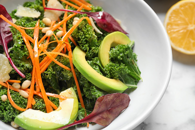 Tasty fresh kale salad on marble table, closeup