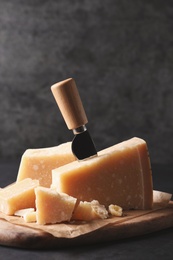 Photo of Delicious parmesan cheese with knife on black table